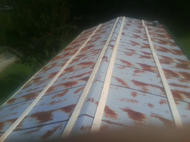 Rusted metal roof panels with new wood purlins before replacement — Storm Damage Roof Repair in Teeds Grove by Roofing Brothers