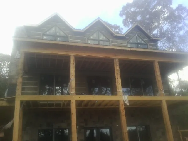 Dormers and porch framing on a large log home under construction — Roof Coating work by our crew in Teeds Grove