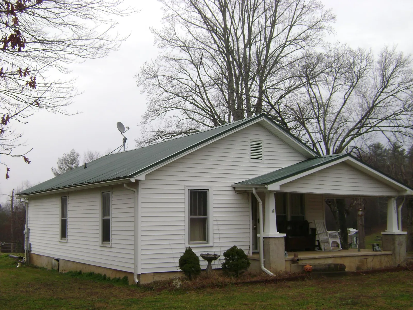 Green metal roof on a white bungalow with a side porch in Teeds Grove
