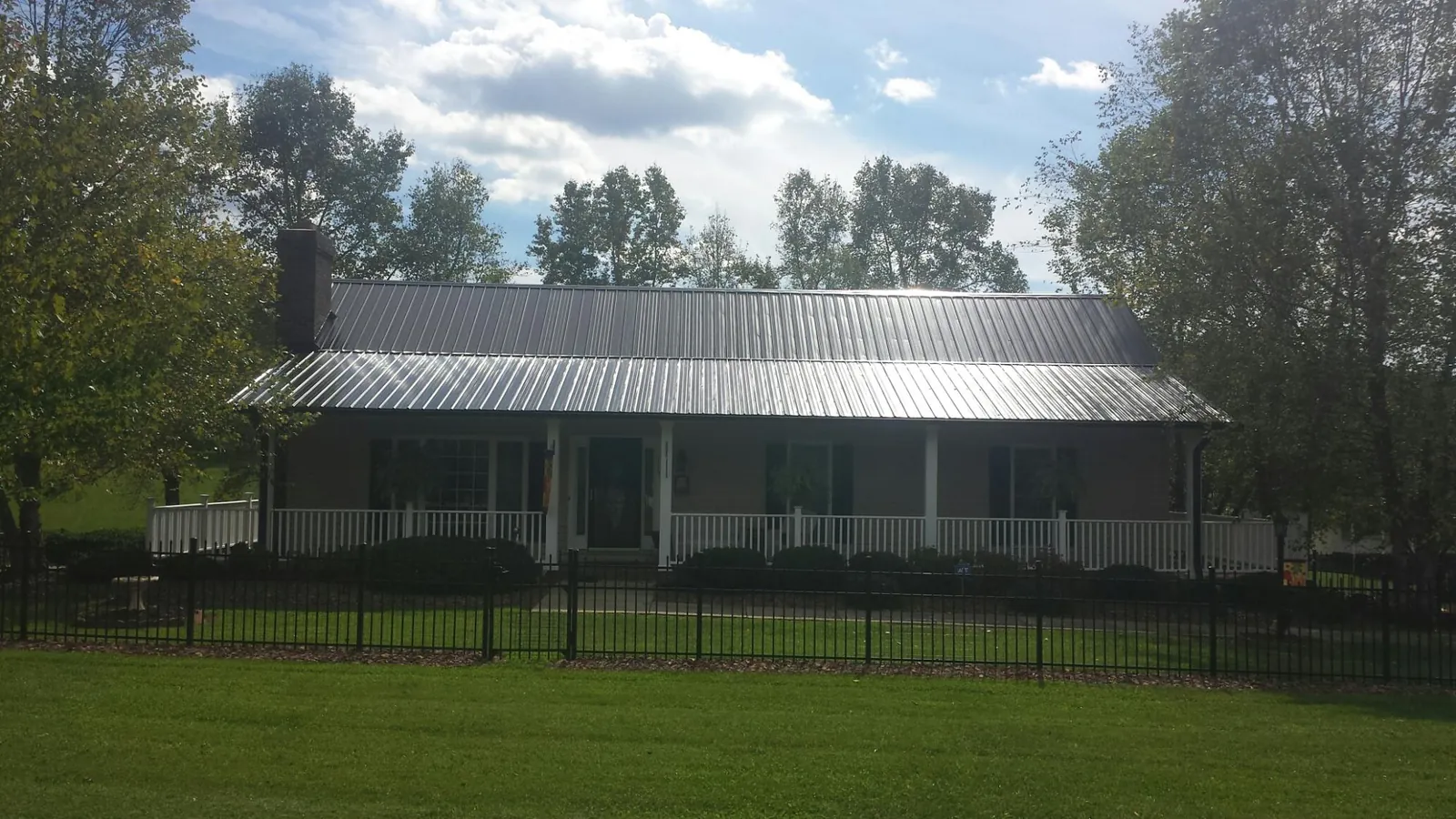 Gray metal roof on a brick ranch with a full width front porch — Gutter Guard Installation work by our crew in Teeds Grove